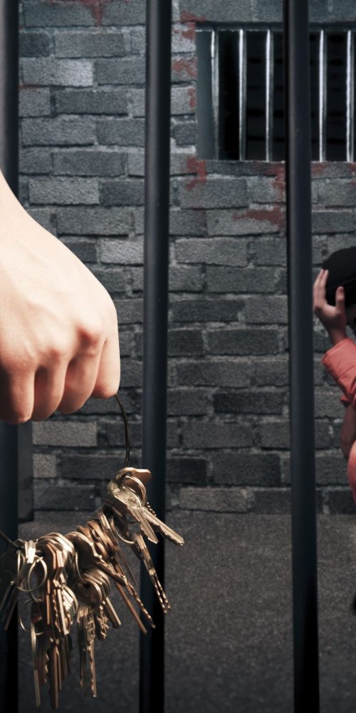 prison guard with keys outside dark prison cell