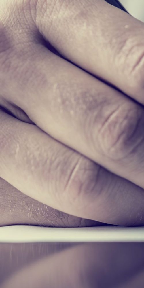 Man signing a document or writing correspondence with a close up view of his hand with the pen and sheet of notepaper on a desk top. With retro filter effect.