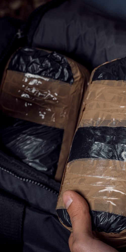 hand with money and packages of cocaine or heroin