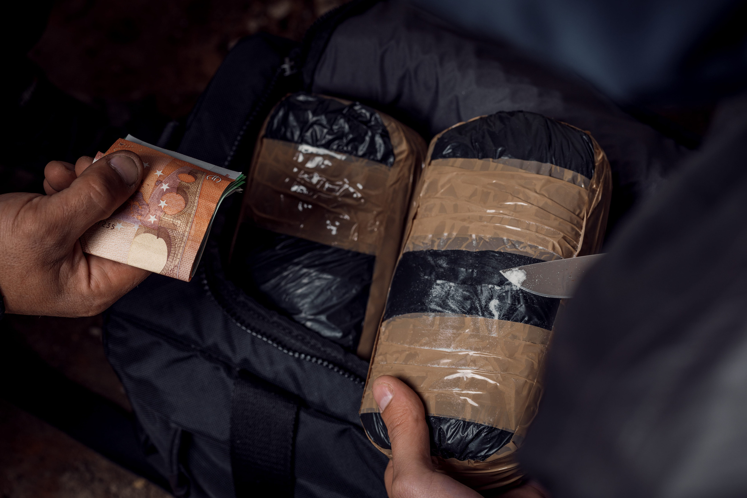 hand with money and packages of cocaine or heroin