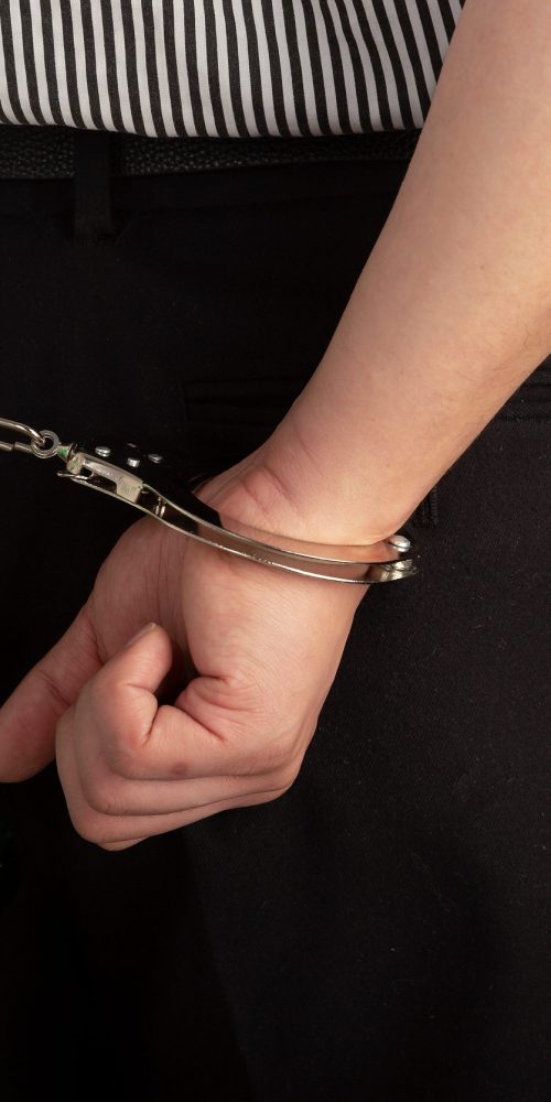 Close up of handcuffed hands with one hand holding a bottle