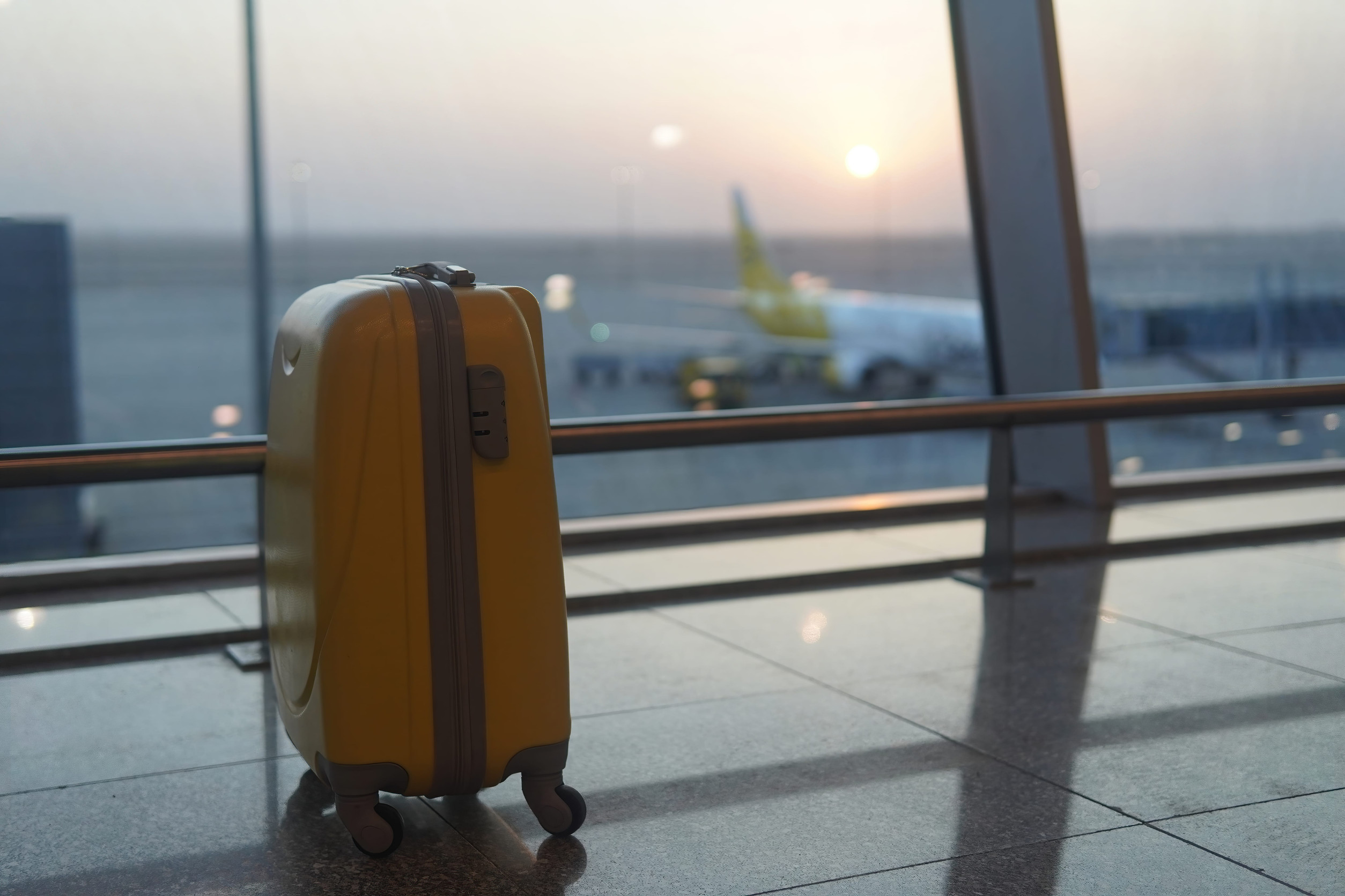 yellow suitcase standing at the airport for the background sunset