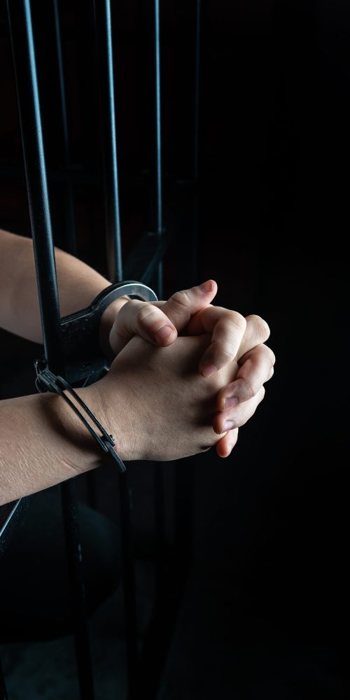 Prisoner in handcuffs praying, prisoner prays in a cell behind bars