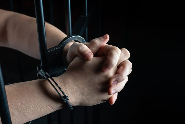 Prisoner in handcuffs praying, prisoner prays in a cell behind bars